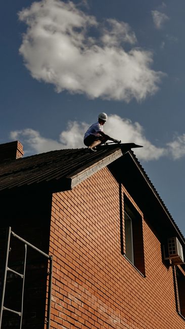 Homeowner examines roof shingles and gutters from the ground with binoculars after a rainstorm.